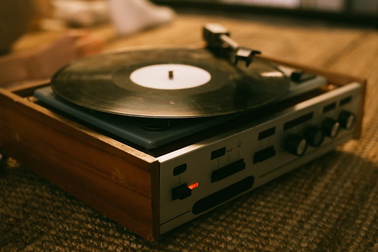 Close-up of a vintage vinyl record player on a textured rug, highlighting analog music ambiance.